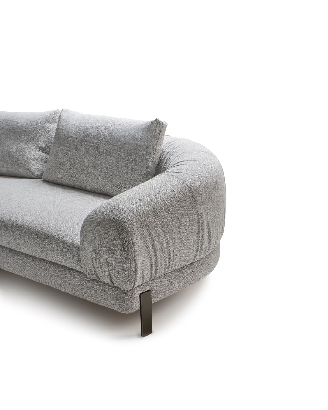 Šviesiai pilka, moderni sofa CRUMBLE su apvalintais porankiais, dviem nugaros pagalvėmis ir plonomis metalinėmis kojelėmi baltame fone