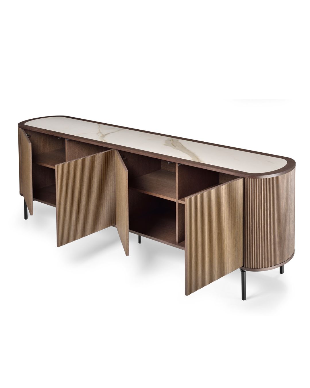 Ilga, minimalistinio dizaino medinė komoda su užapvalintais galais ir vertikaliu frezavimu fasade. Stovi ant plonų juodų metalinių kojelių, paviršius – šiltos riešuto spalvos.