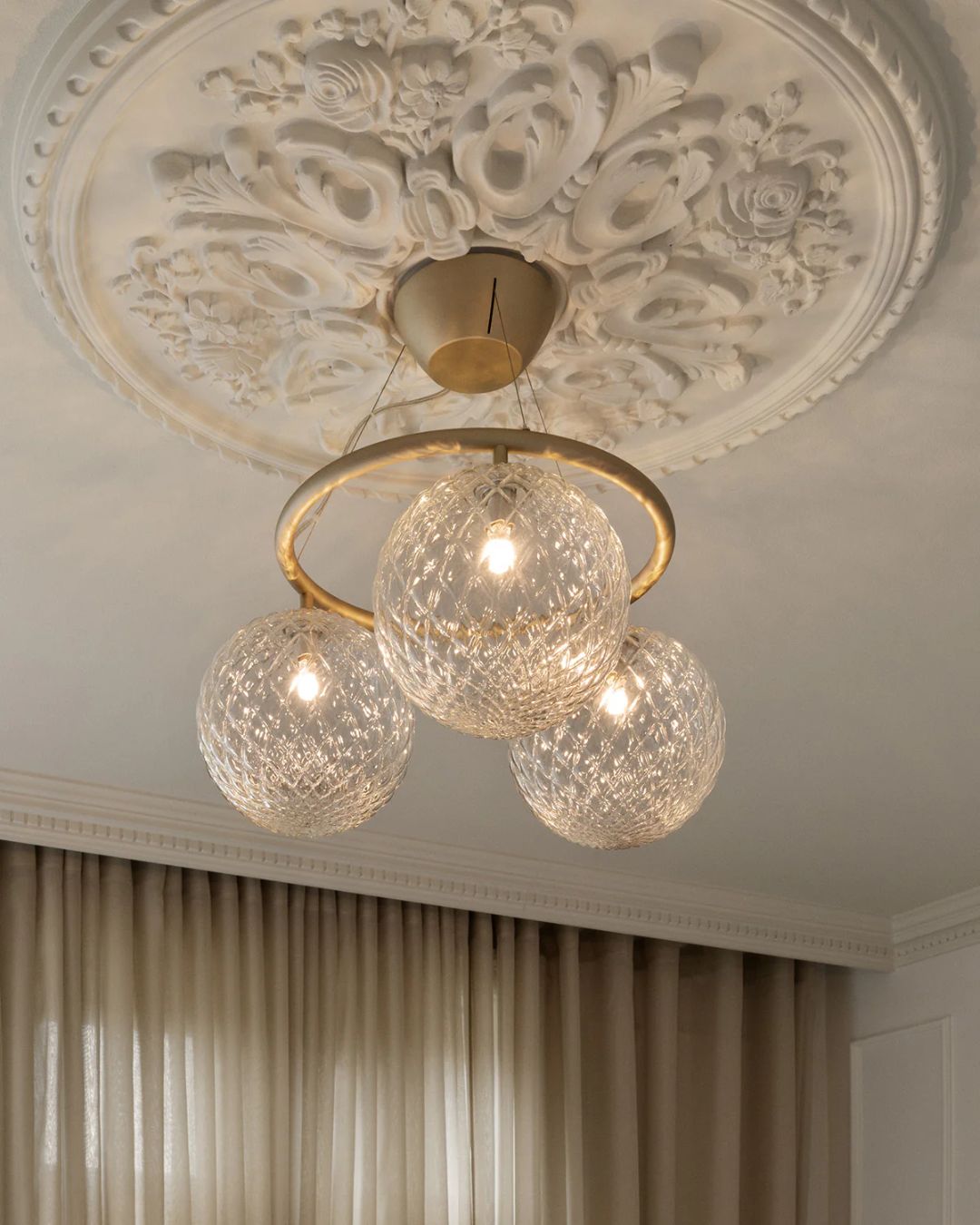 Trijų skaidrių, reljefiniu raštu stiklo gaubtų pakabinamas šviestuvas su poliruoto žalvario žiedu, minimalistinio ir elegantiško dizaino.