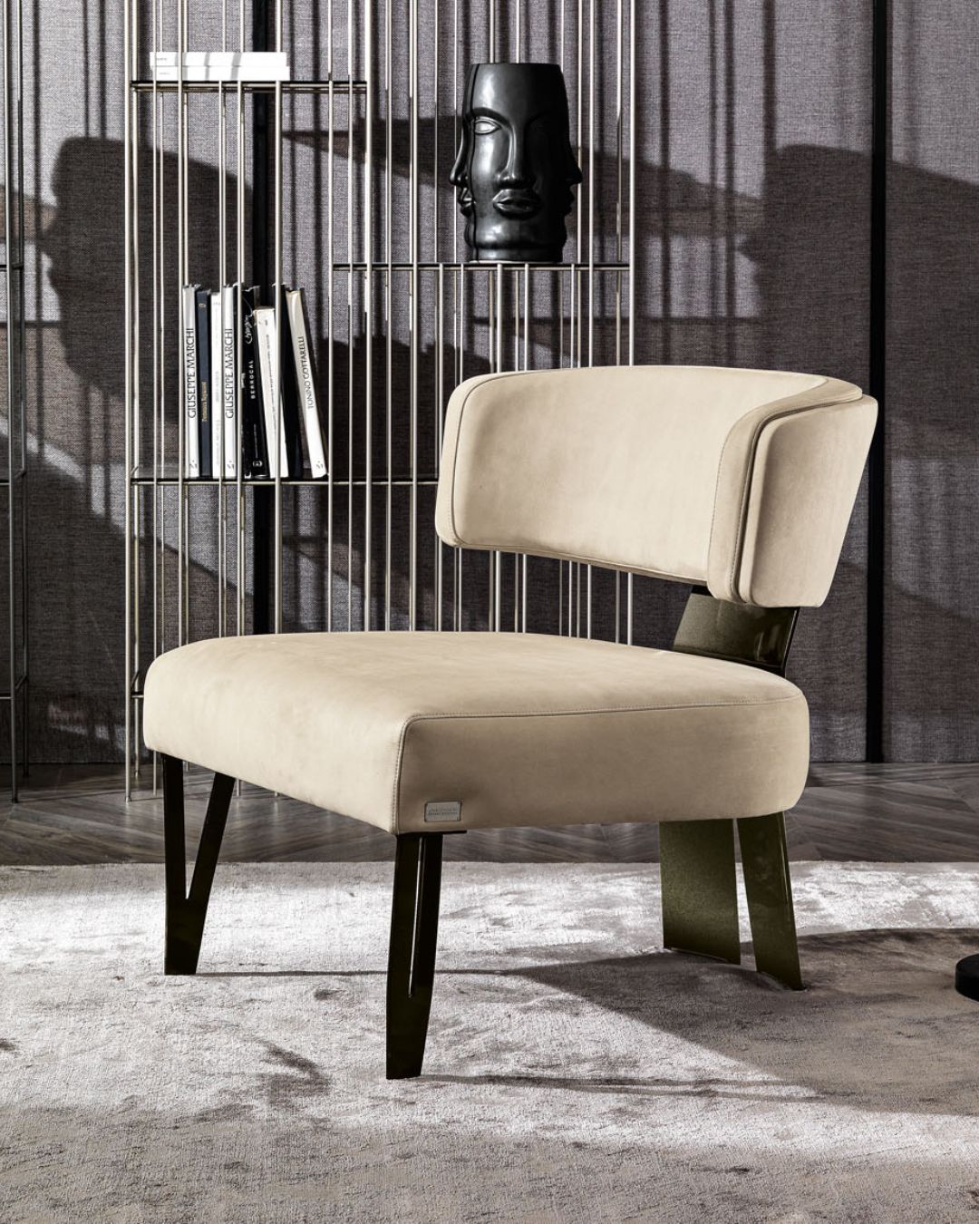 Prabangus itališkas smėlinės spalvos fotelis su plonomis kojelėmis priekyje ir "A" formos stora atrama gale