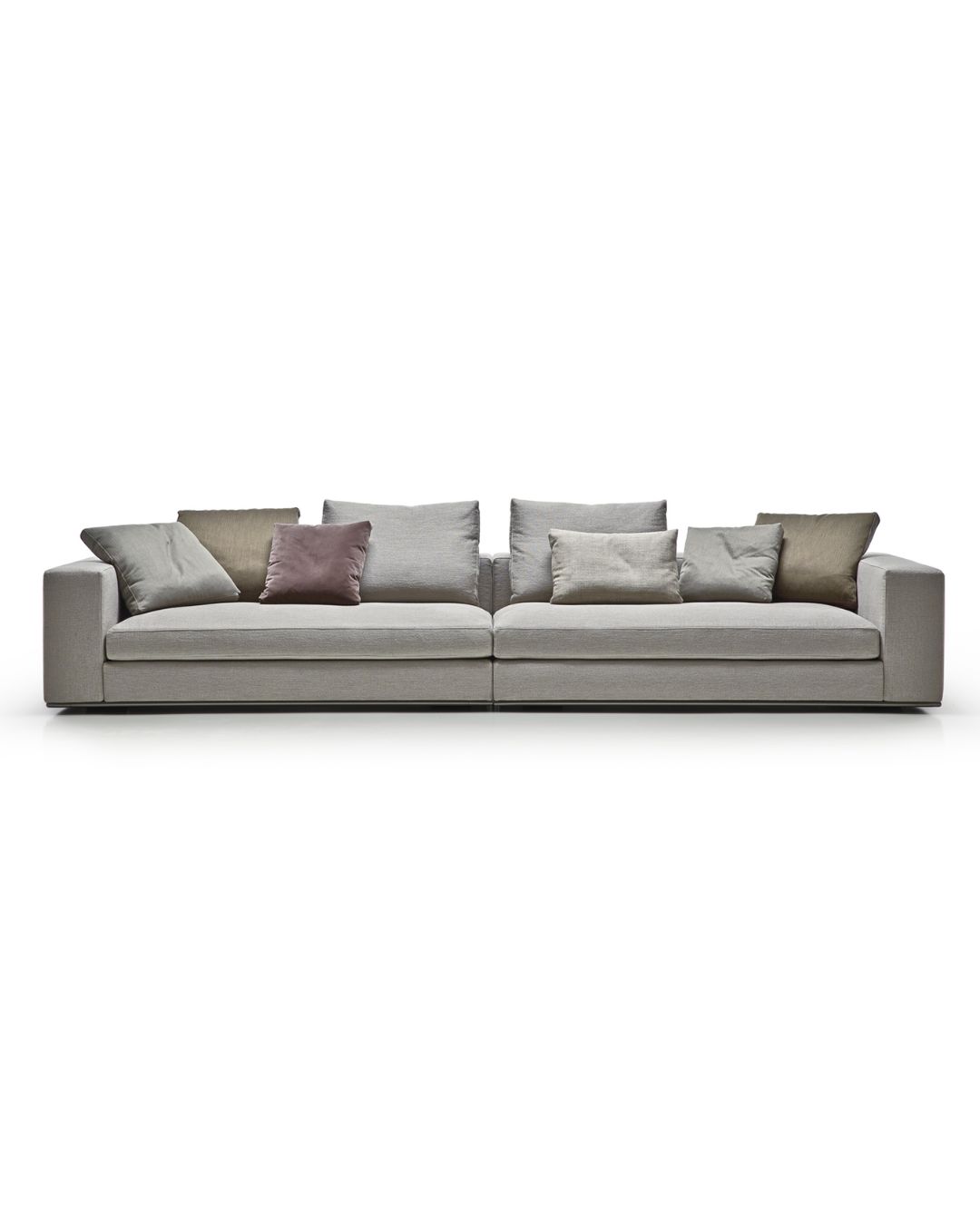 Didelė pilkos spalvos sofa su daug pagalvėlių. Nuotrauka baltame fone.