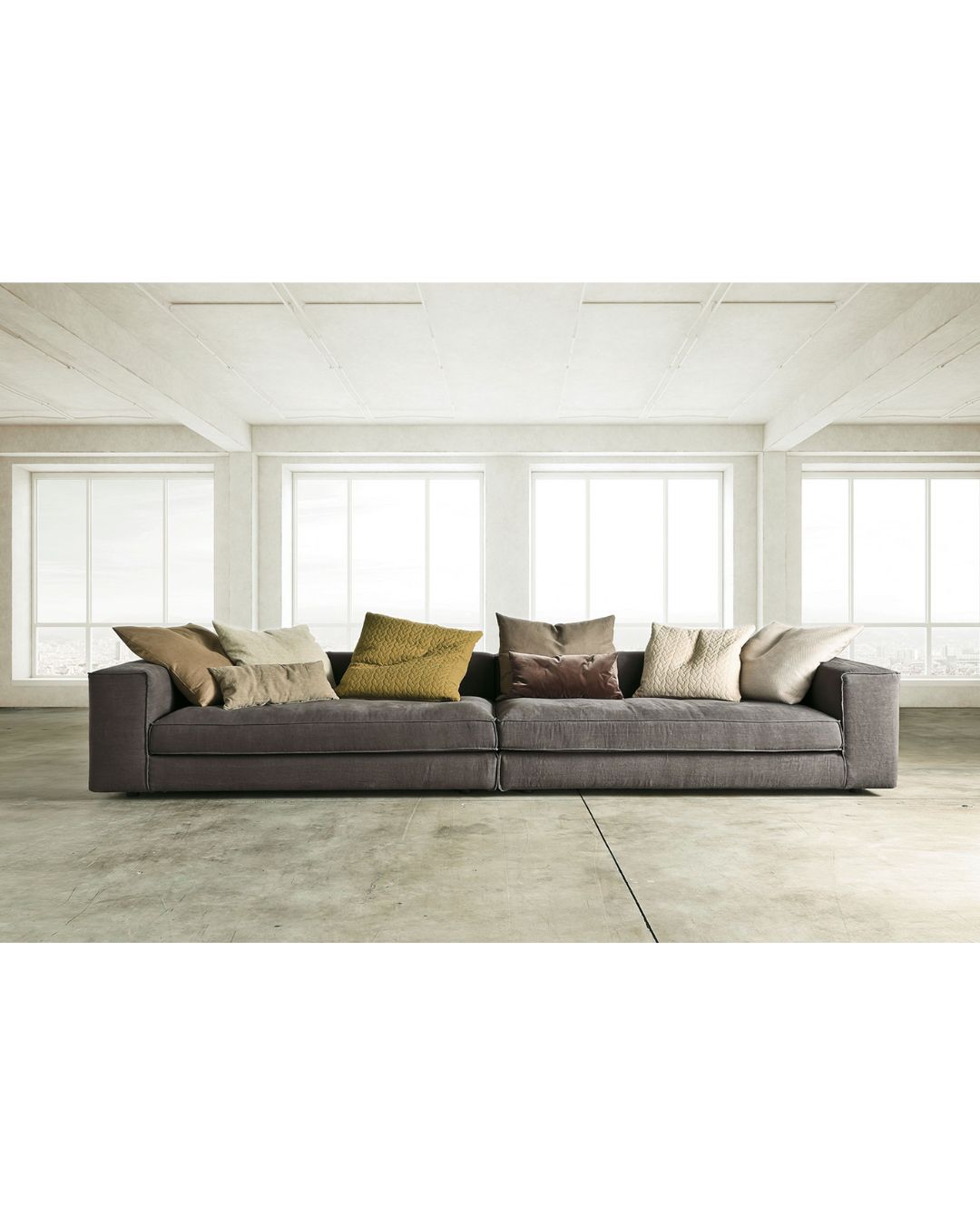 Didžiulė pilka svetainės sofa su daug skirtingos spalvos pagalvėlių