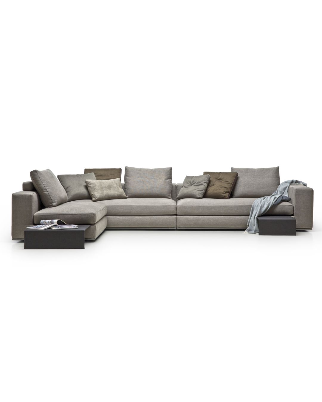 Didelė pilkos spalvos sofa su daug pagalvėlių. Nuotrauka baltame fone.