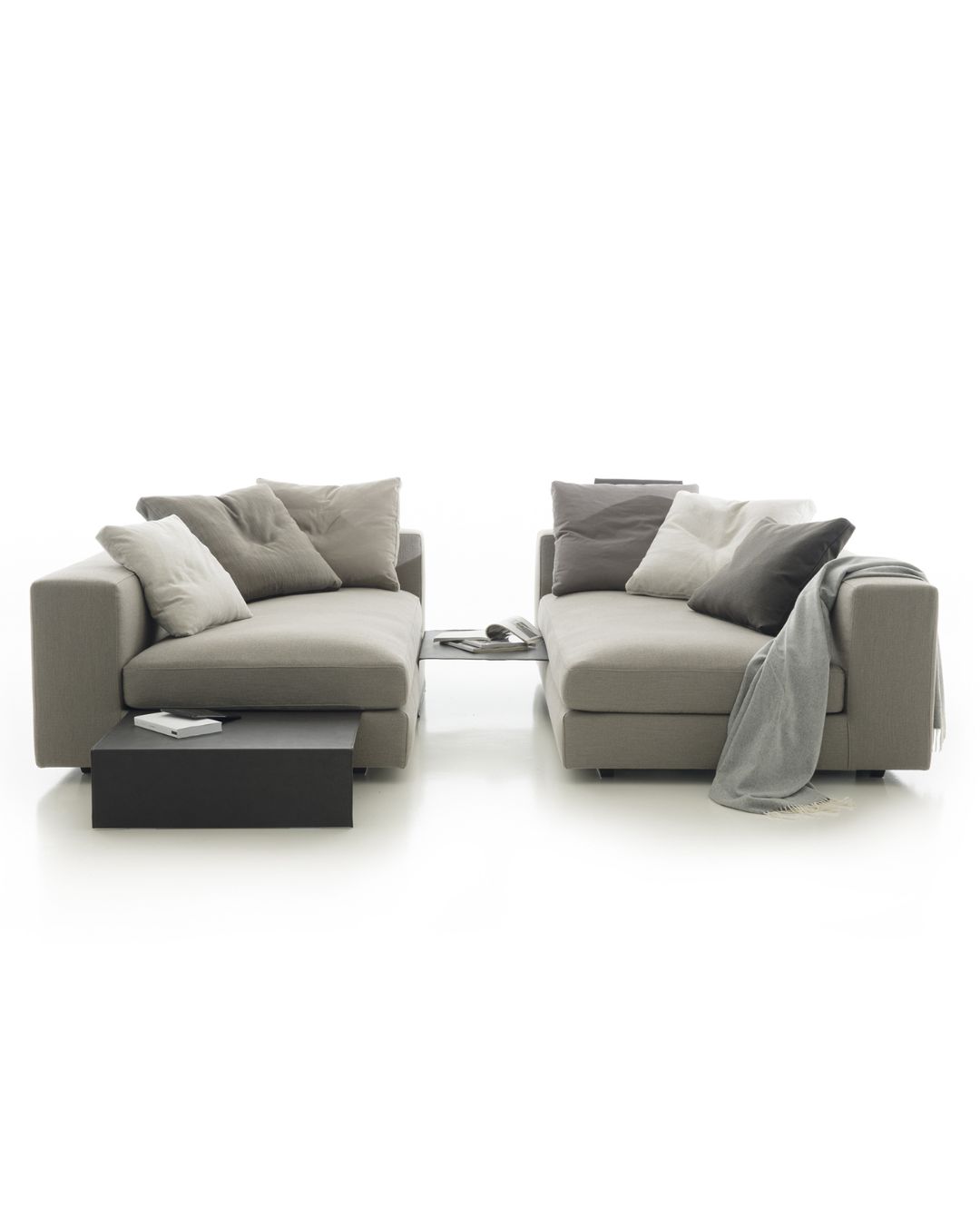 Didelė pilkos spalvos sofa su daug pagalvėlių. Nuotrauka baltame fone.
