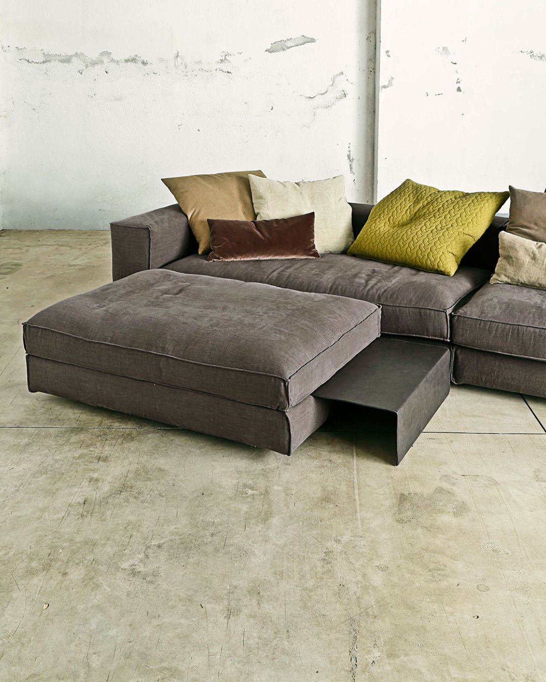 Didžiulė pilka svetainės sofa su daug skirtingos spalvos pagalvėlių